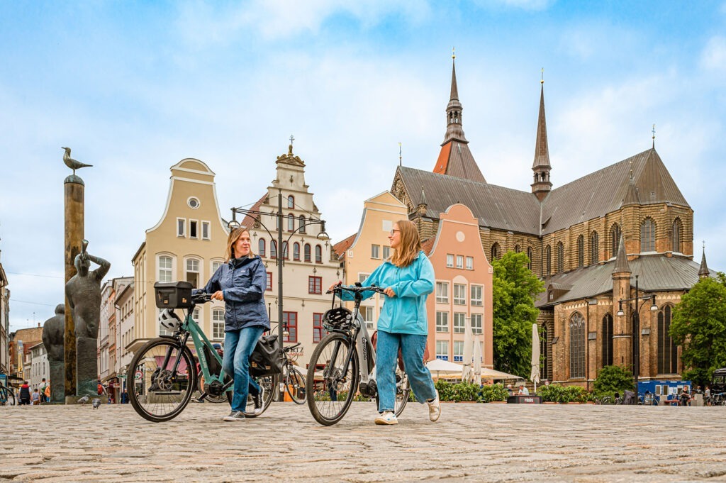 Zwei Frauen schieben ihr Fahhrad auf dem Marktplatz in Rostock