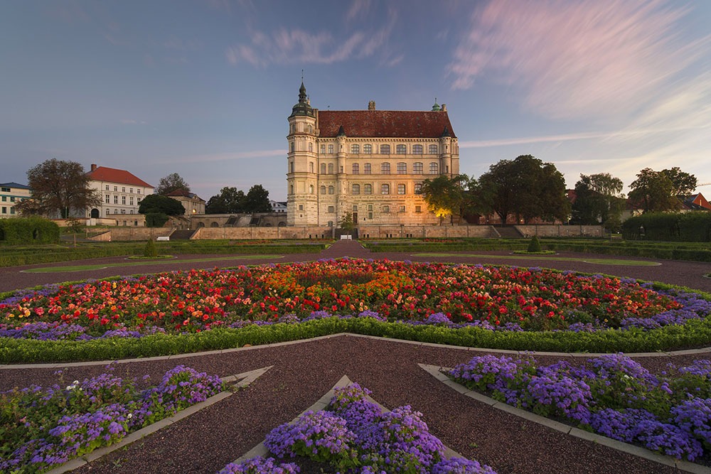 Das Schloss Güstrow im Abendrot zum Sonnenuntergang und mit blühenden Garten erstrahlt